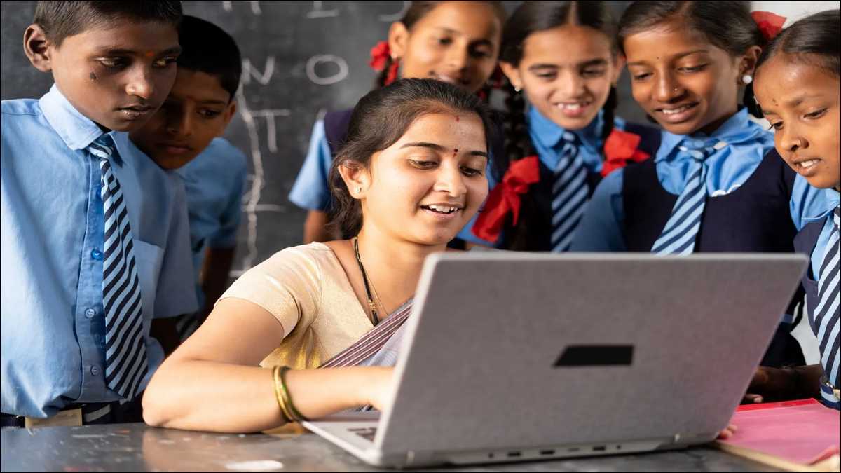 Bihar government school teacher marking attendance on the E-Shikshakosh app outside a rural primary school